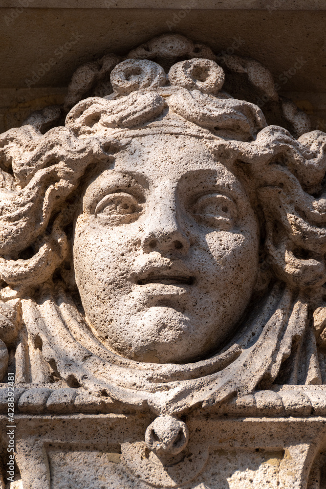 Visage de femme sculpté en pierre, probablement une allégorie de la fortune, ornement de façade d'un immeuble ancien de Paris, France