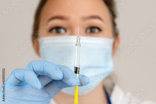 Fototapeta Naklejka Na Ścianę i Meble -  Nurse holds syringe with antiviral vaccine during vaccination campaign. Immunization and disease prevention concept. Selective focused. Close up