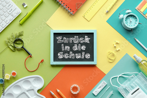 Zuruck in die Schule means or back to school in German language. Corona, covid schnelltest or quick tests, medical mask, stationary. Computer keyboard. Flat lay on layered colored paper background. photo