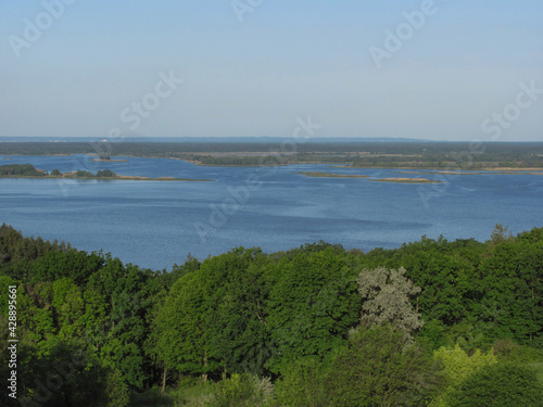 landscape background: green forest, river with islands and blue sky