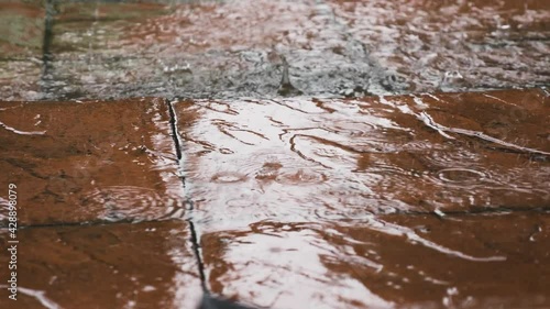 Heavy Rain Falling On Red Pavement. Low Angle, Close Up, Locked Off