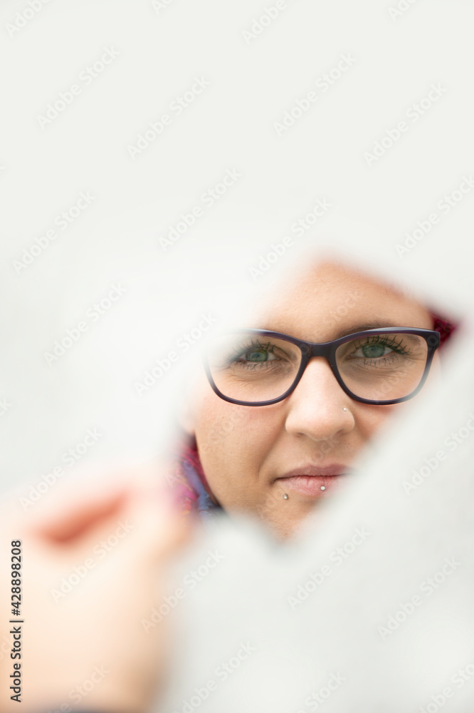 Fototapeta premium Frau mit roten Haaren spiegelt sich in einer Spiegelscherbe, Nahaufnahme