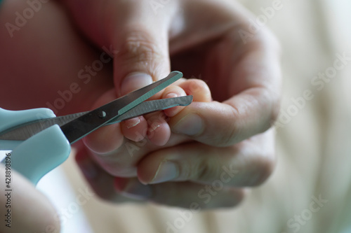 A mother cutting a baby s toenails with scissors.