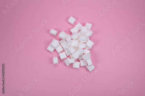 White sugar cubes on pink background composition. Minimal abstract pink background composition. Food concept. Idea of unhealthy lifestyle.