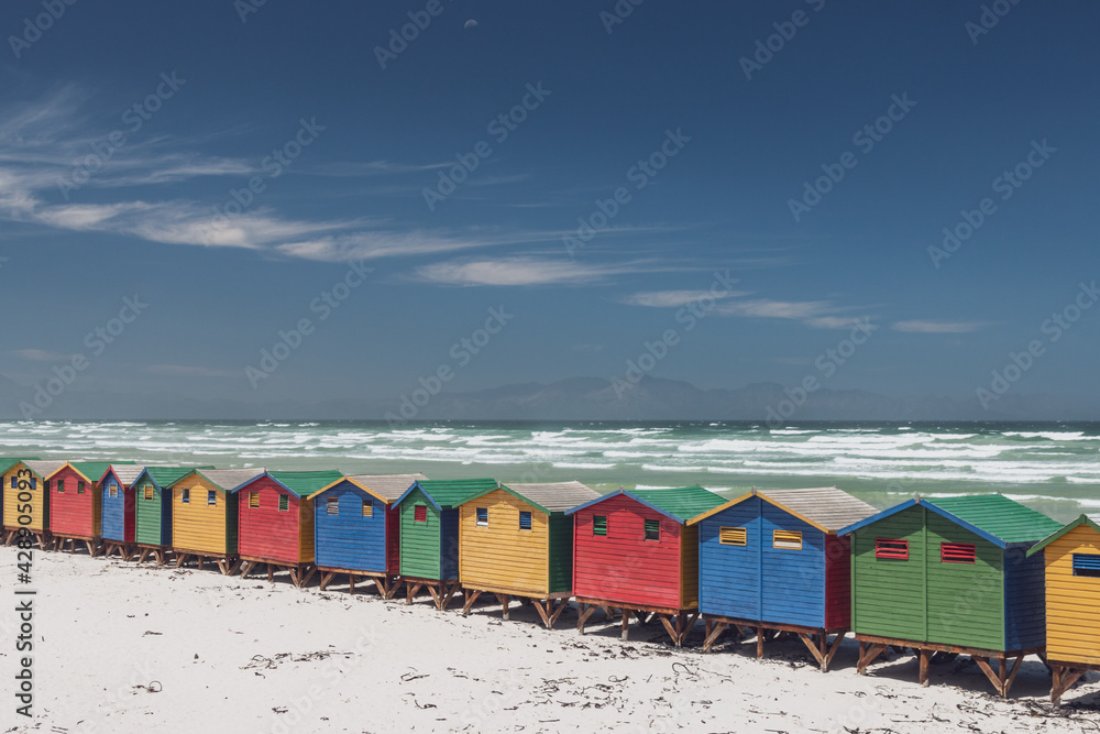 Famous colorful beach houses in Muizenberg near Cape Town, South Africa with Hottentots Holland mountains in the background.