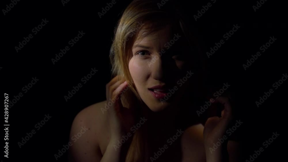 Seductive woman. A young woman, hidden in the shadows, smiles alluringly at the camera. Sexy and tempting. Slowmotion movie. Seductive woman. A young woman, hidden in the shadows, smiles alluringly at the camera. Sexy and tempting. Slowmotion movie.