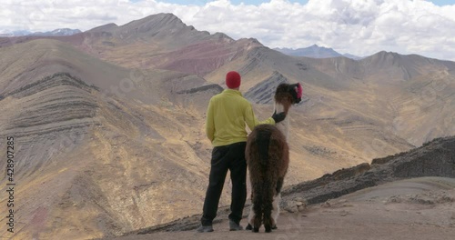 Clip of male model stroking llama and looking out at 7 color rainbow mountain photo