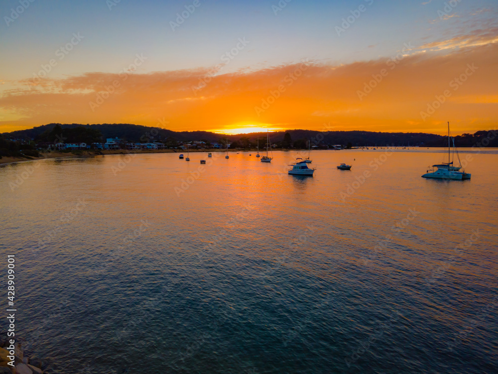 Aerial sunrise waterscape over the channel with orange clouds and boats below Aerial sunrise waterscape over the channel with orange clouds and boats below