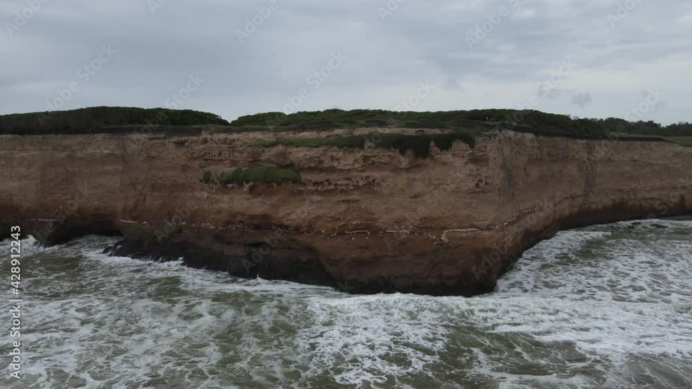 Pan over crashing waves on cliff in a cloudy day in Mar del Plata City, Argentina Pan over crashing waves on cliff in a cloudy day in Mar del Plata City, Argentina