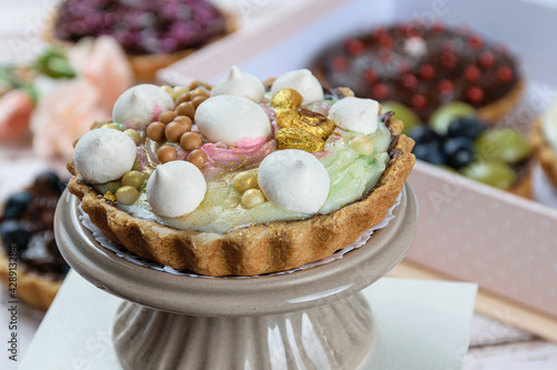 Closeup of pie with buttery dough stuffed with chocolate ganache. Covered with pistachio cream, decorated with meringue, pistachios and white chocolate balls and salted caramel. photo