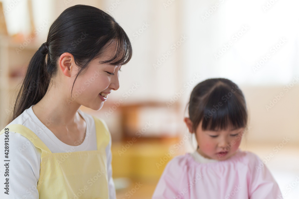 折り紙を折る保育士と園児