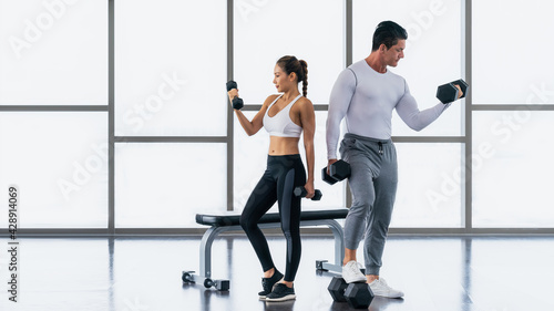 athletic couple workout with dumbbell weight lifting in gym and fitness