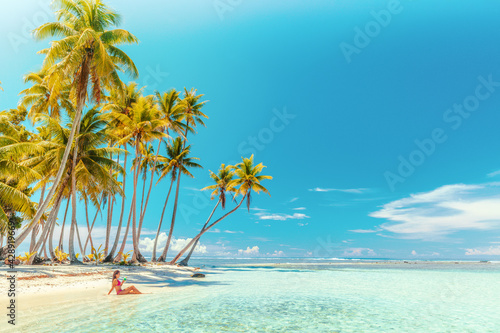 Travel vacation perfect iconic beach with beautiful woman in bikini on private beach island motu relaxing sipping on blue cocktail while sunbathing on French Polynesia travel. Cruise ship destination