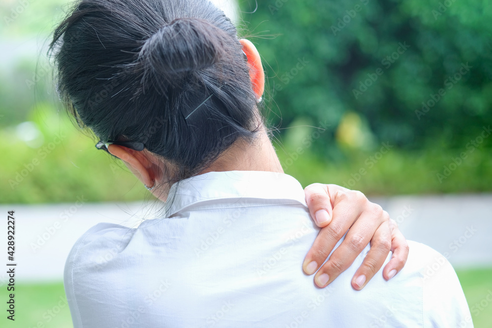 Women have neck pain, shoulder pain, at the park health concept. Women have neck pain, shoulder pain, at the park health concept.