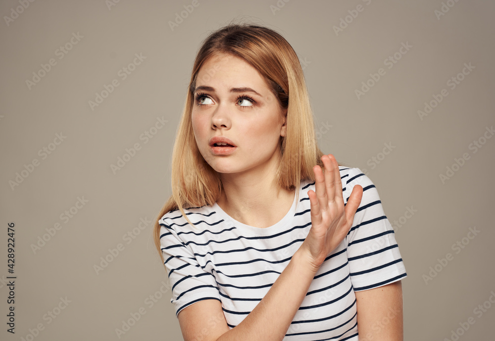 Blond woman with disgust looks to the side and beige background Blond woman with disgust looks to the side and beige background