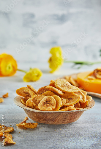 Banana chips healthy food, dry fruits and healthy vegetable chips, healthy vegan snack on background of yellow flowers