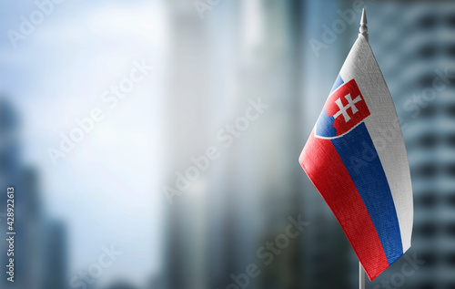 A small flag of Slovakia on the background of a blurred background photo