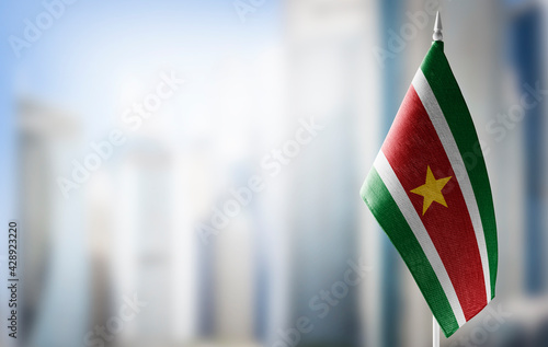 A small flag of Suriname on the background of a blurred background