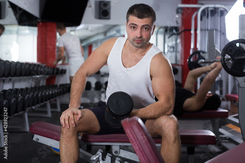 Portrait of athletic man exercising with dumbbells in gym