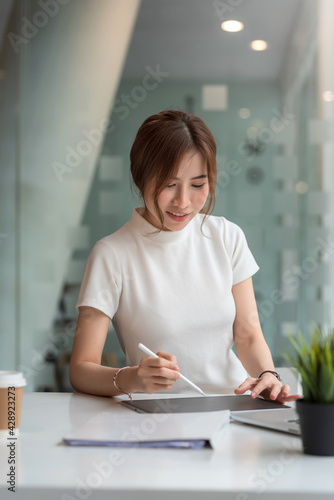 Front view of a beautiful woman working on a tablet at a modern office.