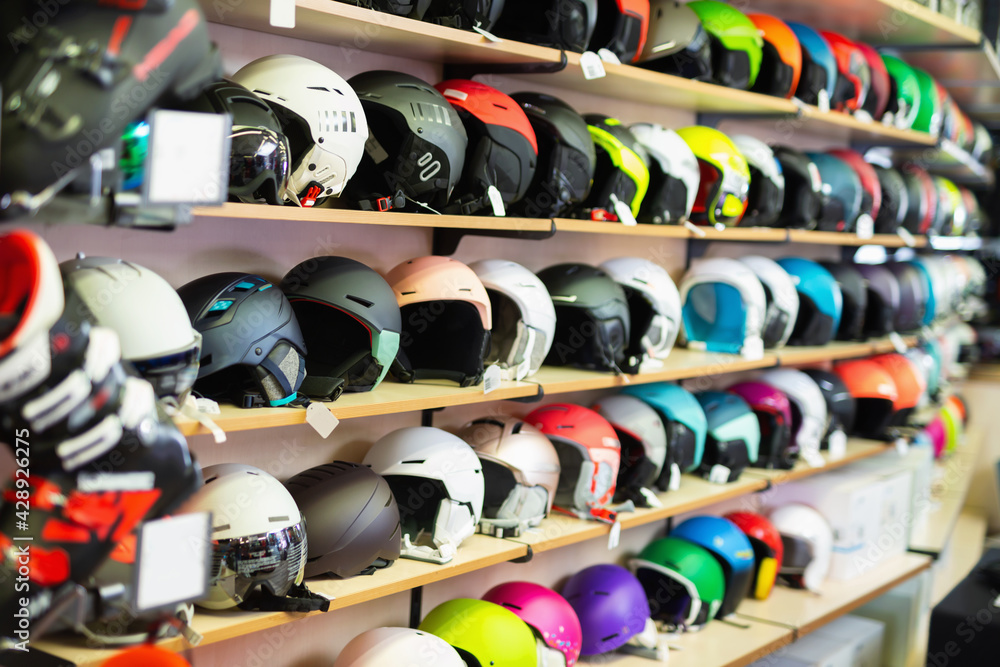 Large selection snowboard and ski helmets on a rack in a sports equipment store