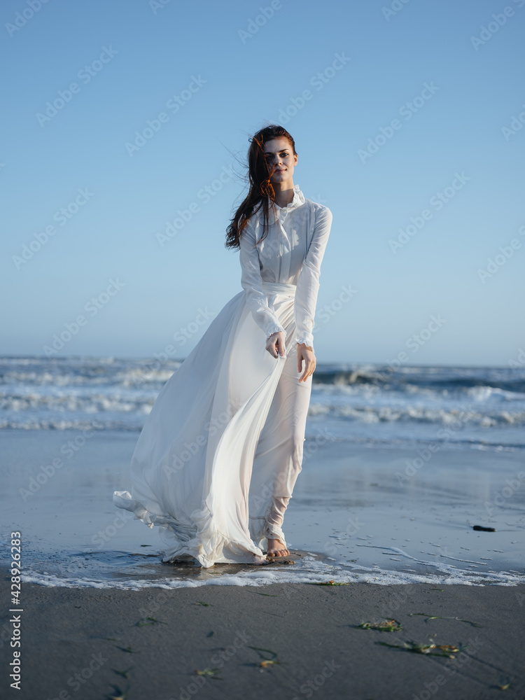 Charming woman in a sundress near the ocean on the shore of the beach model red hair Charming woman in a sundress near the ocean on the shore of the beach model red hair