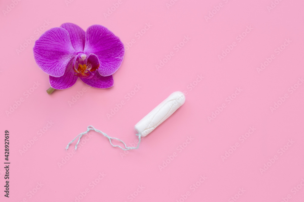 female hyenic tampon on pink background with flower