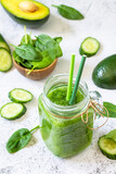 Green smoothie recipe. Healthy diet and nutrition, vegan and alkaline drinks. Fresh smoothie with cucumber, avocado and spinach on a gray stone.