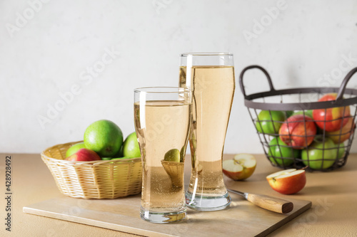 Glasses with apple cider and baskets on table
