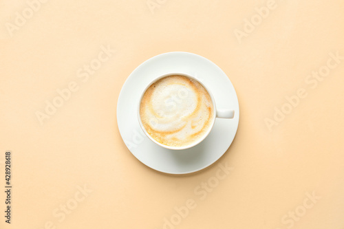 Cup of hot cappuccino coffee on color background photo