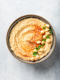 hummus in a ceramic bowl on a light background, top view
