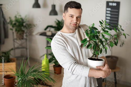 Young man taking care of plants at home