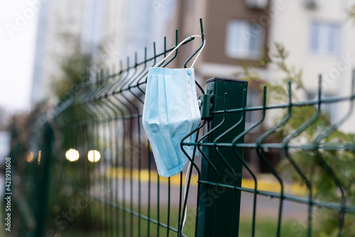 The concept of ending a coronavirus pandemic. A protective face mask hanging from an old cast-iron fence. Freedom.