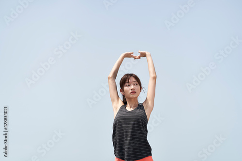 young asian woman stretching arms outdoors