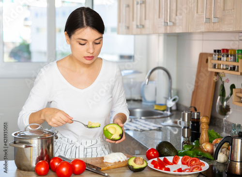 Young attractive woman standing in home kitchen  preparing vegetable dish