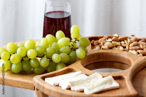 Serving wooden table for wine, glasses and snacks. Handmade segmented Portion wooden table. Grapes, cheese, wine and nuts.  