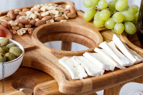 Serving wooden table for wine, glasses and snacks. Handmade segmented Portion wooden table. Grapes, cheese, wine and nuts.  