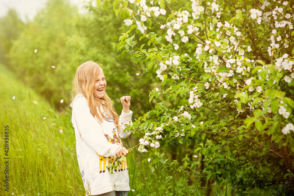 Happy girl playing in spring blooming apple orchard, selective focus Happy girl playing in spring blooming apple orchard, selective focus