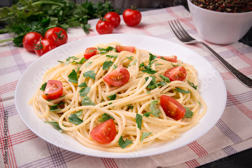 Pasta spaghetti with cherry tomatoes and parsley on a light background.