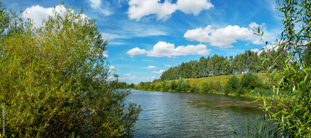 Sunny bright landscape with small river and green trees.Beautiful summer nature scene.