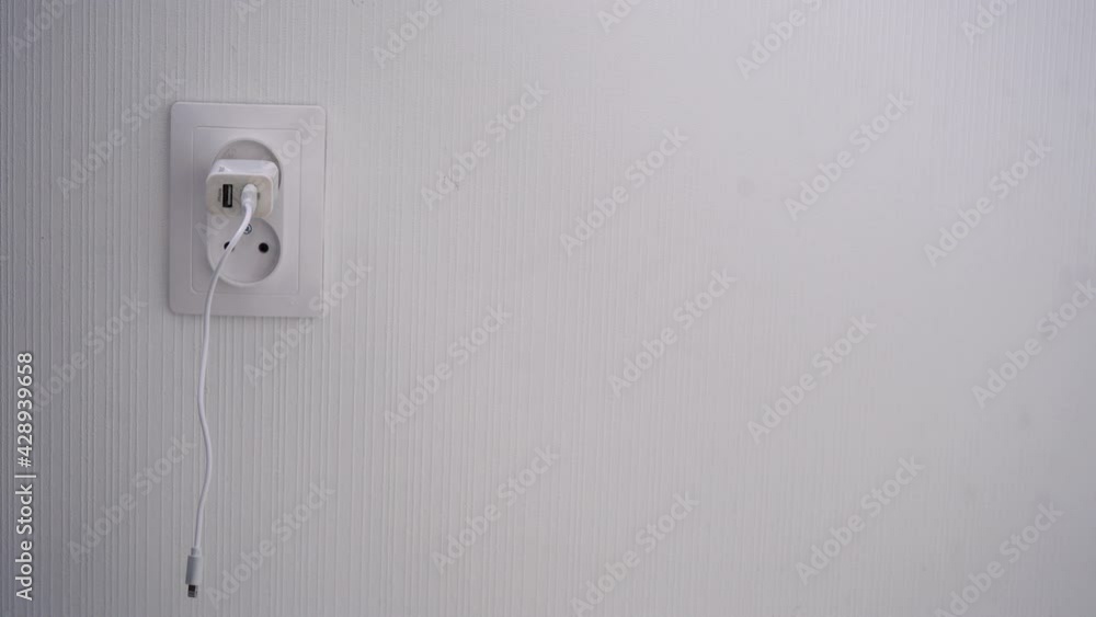 phone charger plugged into a wall socket phone charger plugged into a wall socket