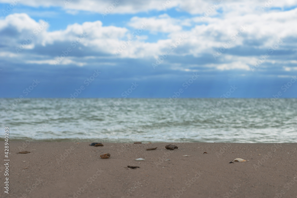 Cloudy sky over water surface and sandy shore.