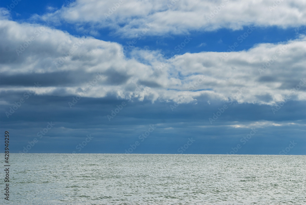 The surface of the sea under a cloudy blue sky.