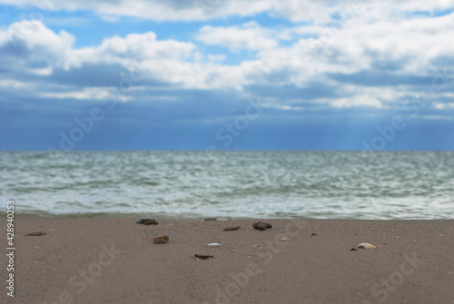 Cloudy sky over water surface and sandy shore.