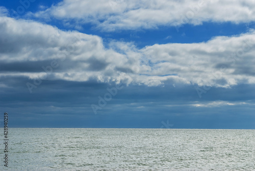 The surface of the sea under a cloudy blue sky.