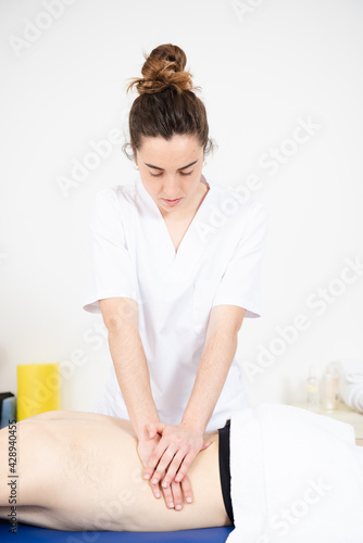 Masseuse treating the back and waist of a patient in a physiotherapy center.