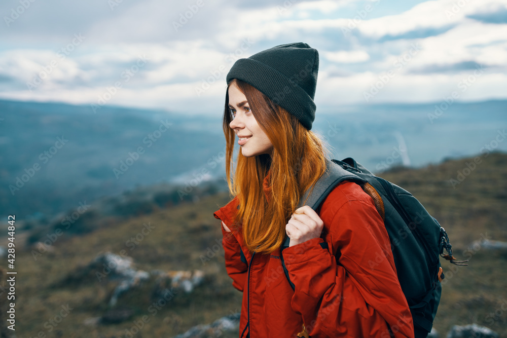 woman jacket hats looking at the mountain in the distance blue sky clouds Model backpack woman jacket hats looking at the mountain in the distance blue sky clouds Model backpack