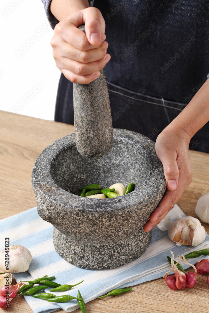Woman use stone Mortar and Pestle for cooking green curry paste