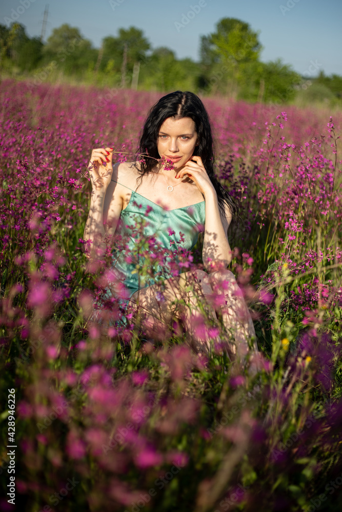 Girl in a turquoise dress in a blooming field Girl in a turquoise dress in a blooming field