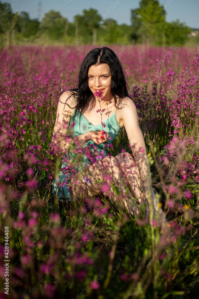 Girl in a turquoise dress in a blooming field